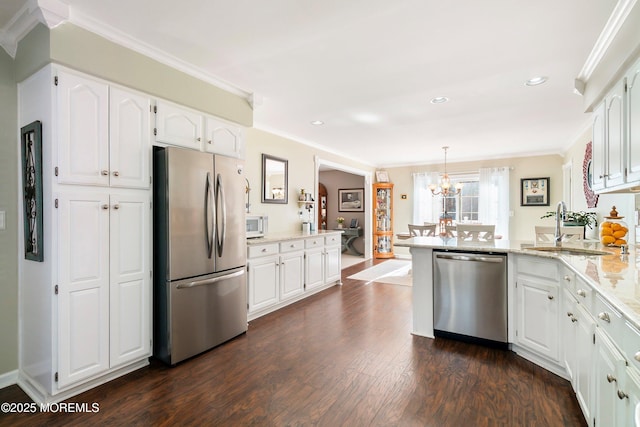 kitchen featuring stainless steel appliances, a peninsula, a sink, white cabinetry, and crown molding