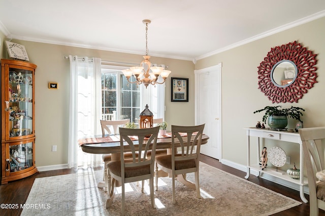 dining space featuring dark wood-type flooring, a chandelier, ornamental molding, and baseboards