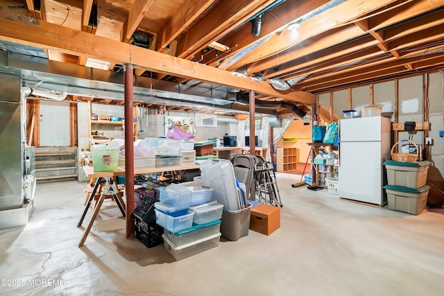 unfinished basement with freestanding refrigerator and stairway