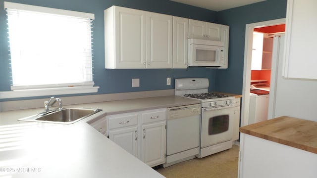 kitchen with white appliances, washer / dryer, white cabinets, butcher block counters, and a sink