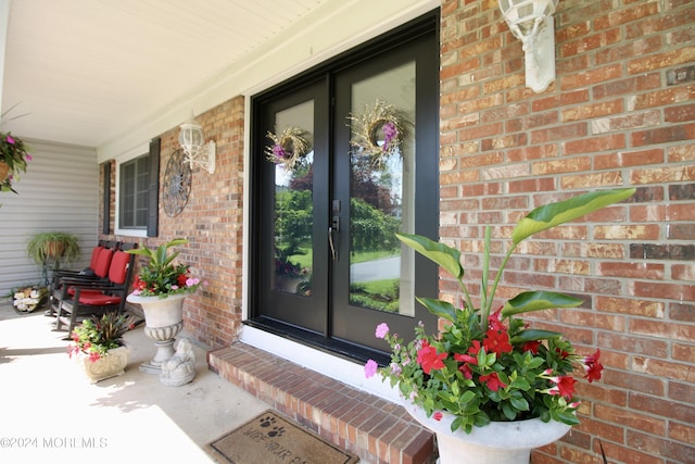 entrance to property featuring a porch and brick siding