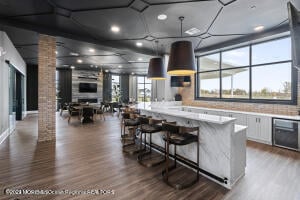 kitchen featuring decorative columns, wood finished floors, light countertops, a kitchen bar, and white cabinetry