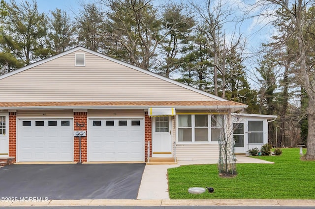 view of front of house featuring aphalt driveway, roof with shingles, a front lawn, and brick siding