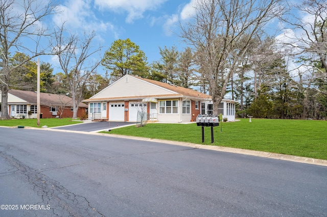 view of front of home featuring an attached garage, brick siding, aphalt driveway, and a front yard