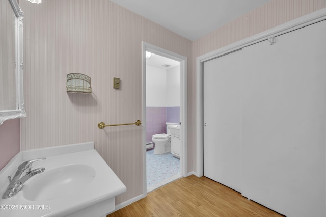 bathroom featuring toilet, wallpapered walls, wood finished floors, and vanity