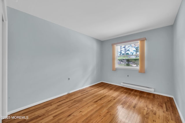 spare room featuring baseboards, baseboard heating, and hardwood / wood-style floors