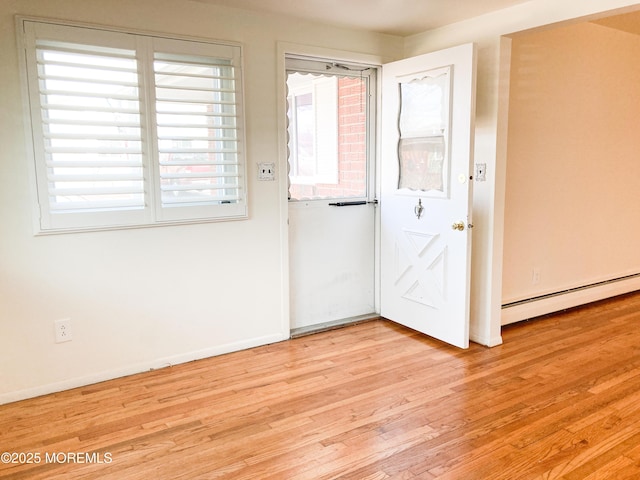 unfurnished room with a baseboard radiator, baseboards, and light wood-style flooring