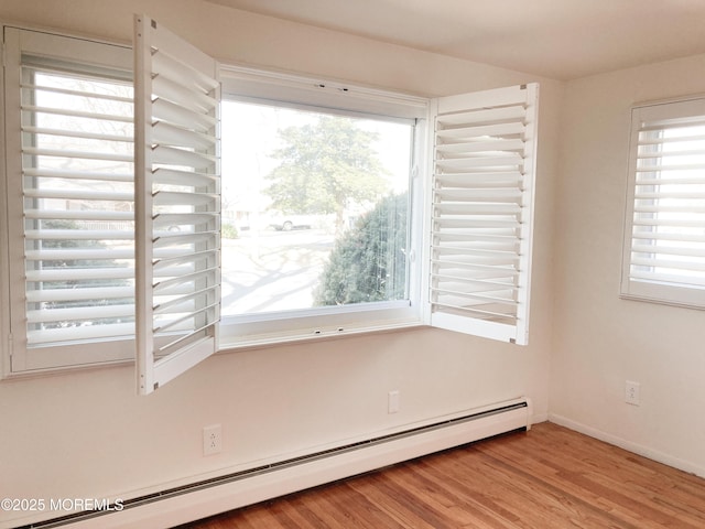 spare room with baseboards, baseboard heating, and wood finished floors