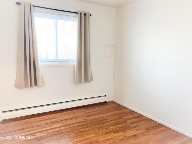 empty room featuring baseboards, baseboard heating, and wood finished floors