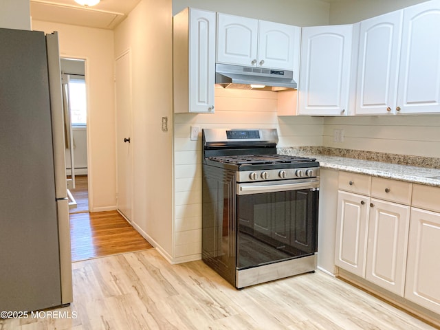 kitchen with light wood finished floors, appliances with stainless steel finishes, white cabinetry, and under cabinet range hood