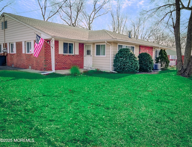 ranch-style home featuring central AC, brick siding, a front lawn, and roof with shingles