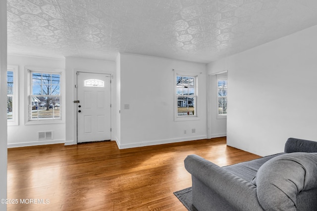 foyer entrance featuring wood finished floors, visible vents, and baseboards