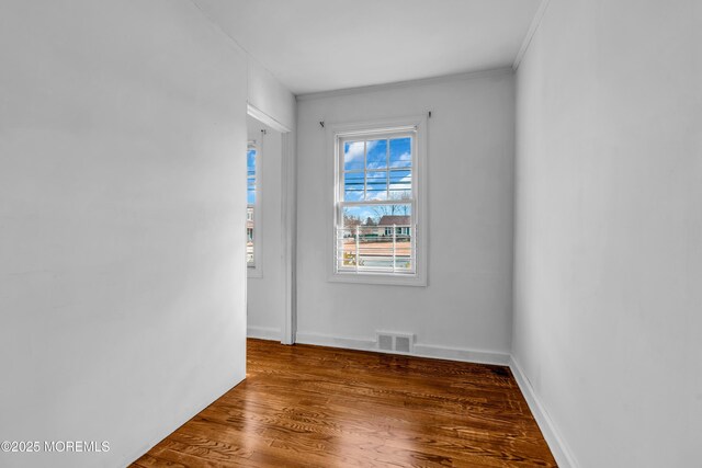 unfurnished room featuring baseboards, crown molding, visible vents, and wood finished floors