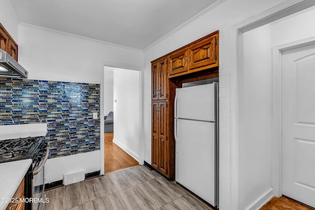 kitchen featuring stainless steel range with gas cooktop, crown molding, light countertops, visible vents, and freestanding refrigerator