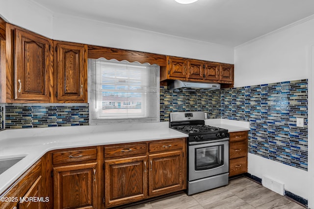 kitchen with visible vents, gas range, ventilation hood, crown molding, and light countertops