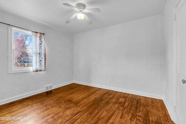 spare room featuring visible vents, baseboards, ceiling fan, and wood finished floors