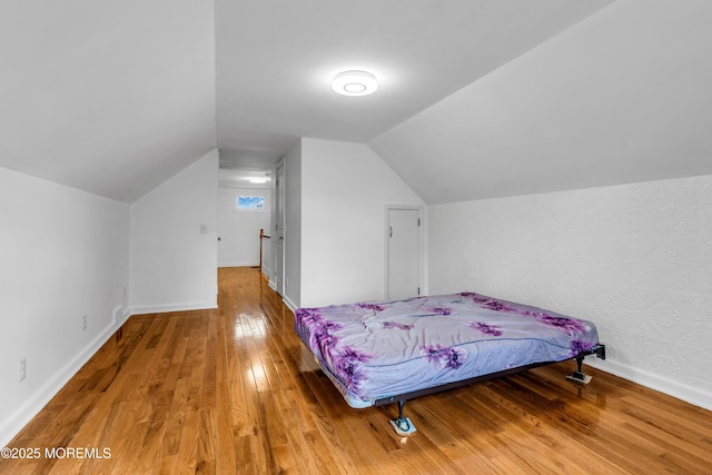 bedroom featuring baseboards, vaulted ceiling, and hardwood / wood-style floors