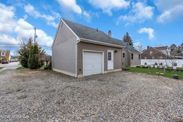 garage with gravel driveway and fence