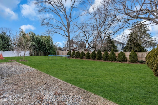 view of yard with a trampoline and a fenced backyard