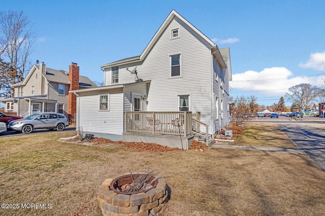 back of house featuring a lawn and a fire pit