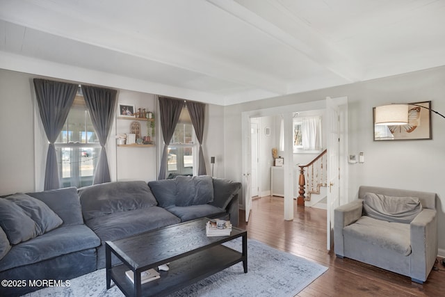 living area featuring dark wood-style floors, stairs, baseboards, and beamed ceiling