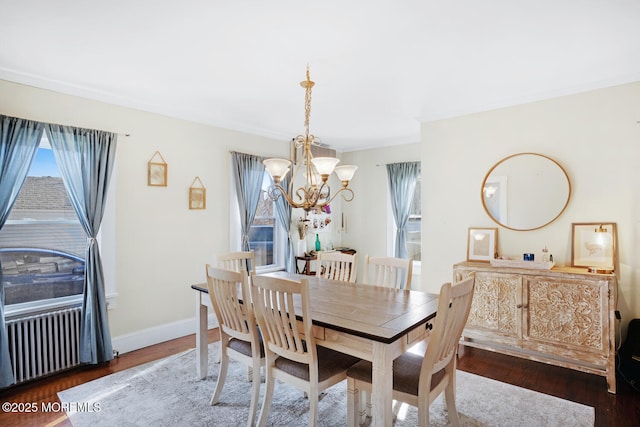 dining space with dark wood-style floors, a notable chandelier, and baseboards