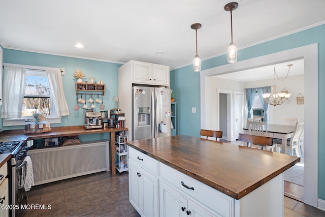 kitchen with radiator, wood counters, a center island, stainless steel appliances, and white cabinetry