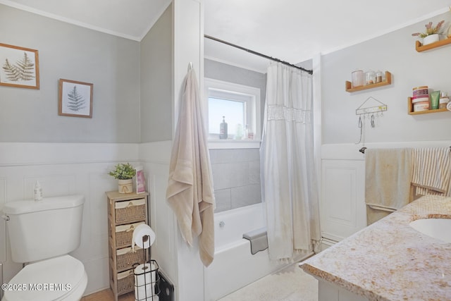 full bathroom with shower / bath combo, toilet, a wainscoted wall, crown molding, and vanity