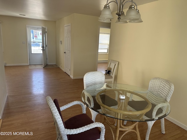 dining area featuring a baseboard radiator, an inviting chandelier, baseboards, and wood finished floors