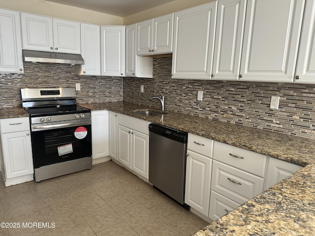 kitchen featuring under cabinet range hood, stainless steel appliances, a sink, white cabinets, and dark stone counters