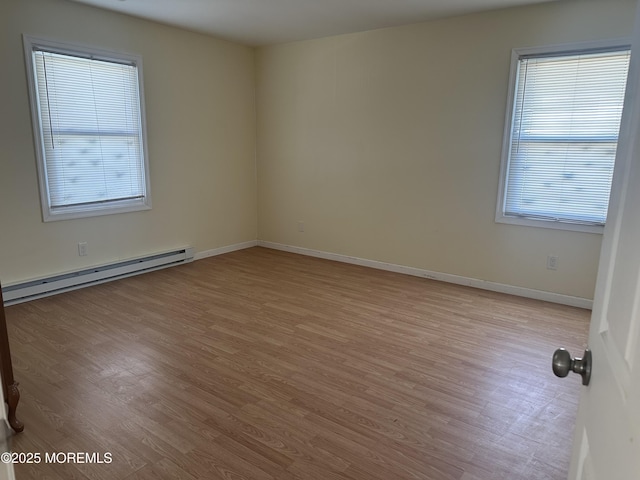 spare room with baseboards, light wood-type flooring, a baseboard radiator, and a healthy amount of sunlight