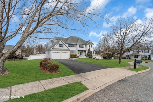 view of front facade with a garage, driveway, a front yard, and fence