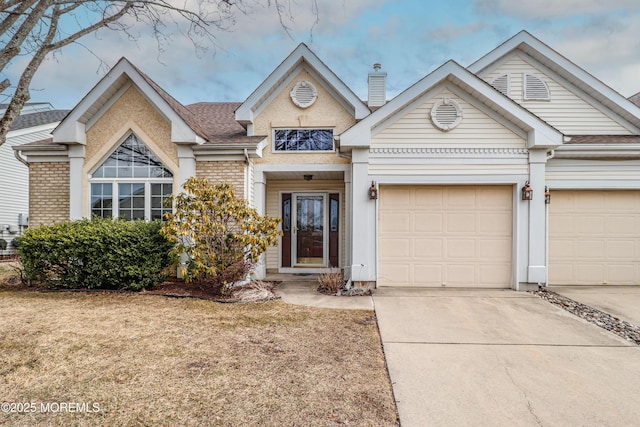 view of front of home with brick siding, a chimney, a shingled roof, concrete driveway, and an attached garage