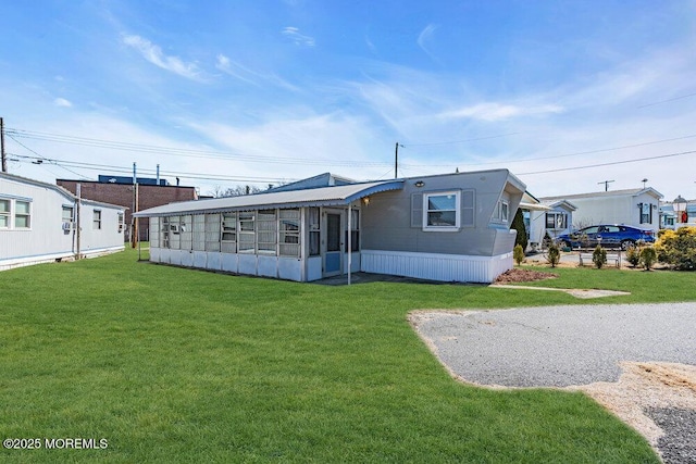 rear view of property with a sunroom and a lawn