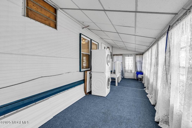 unfurnished sunroom featuring a paneled ceiling, stacked washing maching and dryer, and vaulted ceiling