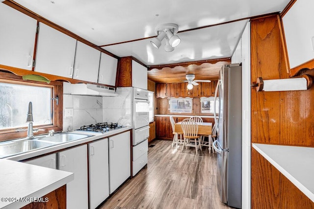 kitchen featuring light countertops, a ceiling fan, light wood-style floors, a sink, and white appliances