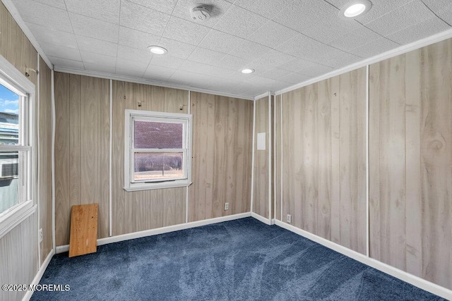 spare room featuring carpet floors, crown molding, recessed lighting, wood walls, and baseboards