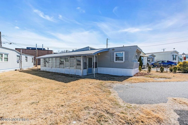 manufactured / mobile home featuring a sunroom and a front lawn