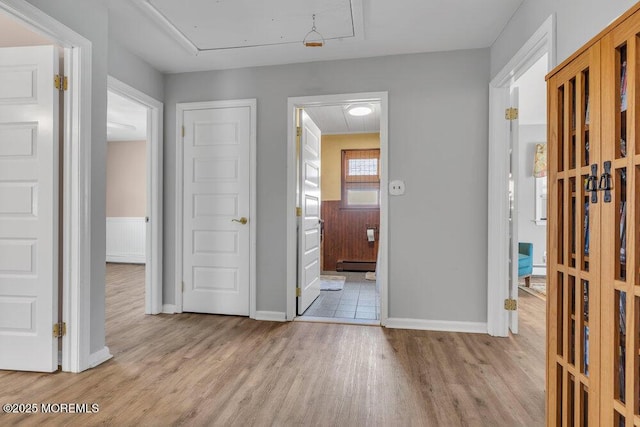 interior space with baseboards, baseboard heating, attic access, and wood finished floors