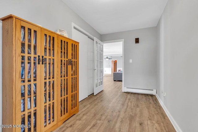 hall featuring wood finished floors, baseboards, and baseboard heating