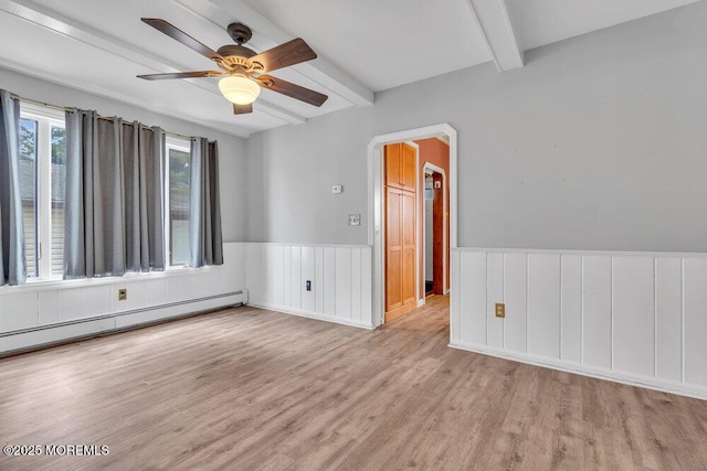 spare room with beam ceiling, baseboard heating, a wainscoted wall, and wood finished floors