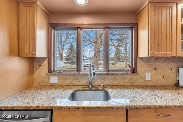 kitchen with dishwasher, light stone counters, backsplash, and a sink