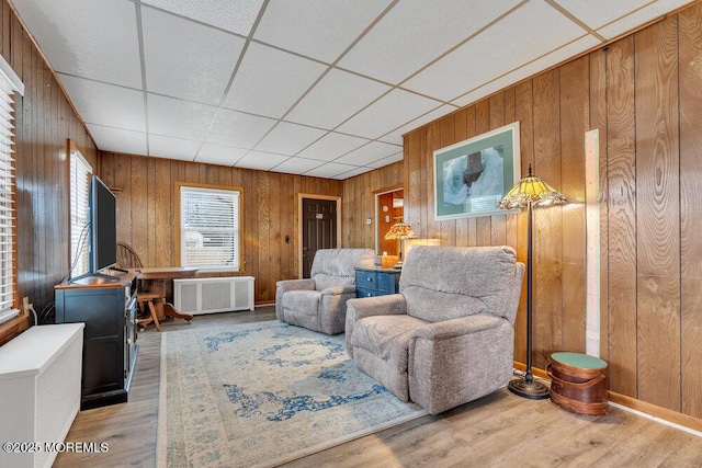 living room featuring wooden walls, radiator heating unit, a paneled ceiling, and wood finished floors