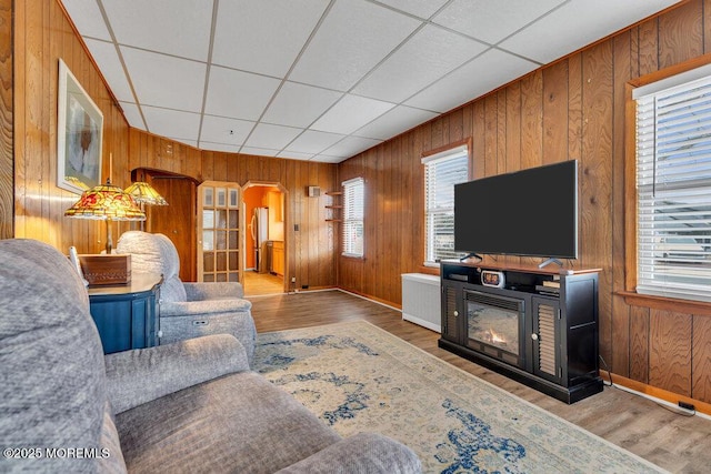 living area with wood walls, a paneled ceiling, and wood finished floors