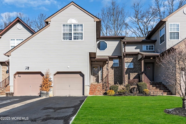 view of front of home featuring brick siding, a garage, aphalt driveway, and a front lawn