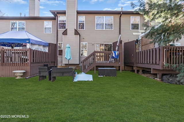 back of house with a yard, a wooden deck, and a chimney