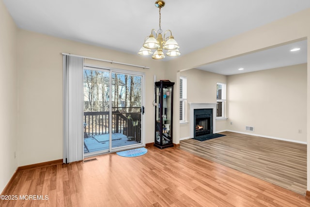 unfurnished living room with a fireplace with flush hearth, wood finished floors, visible vents, and baseboards