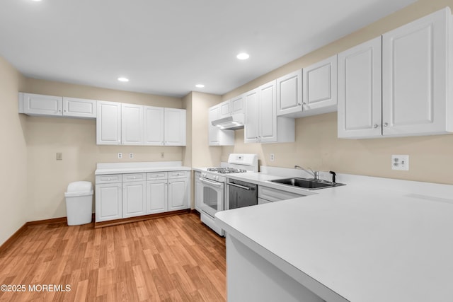 kitchen featuring light wood-type flooring, a sink, under cabinet range hood, light countertops, and white gas range