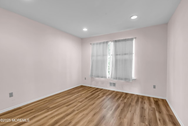 spare room featuring recessed lighting, wood finished floors, visible vents, and baseboards