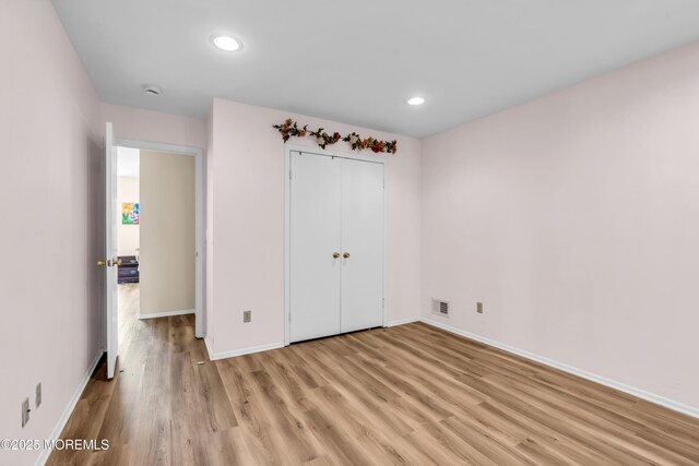 unfurnished bedroom with light wood finished floors, visible vents, baseboards, recessed lighting, and a closet